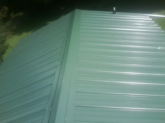 New green metal panels meeting at the ridge of a roof — Flat Roof Repair work by our crew in Seaford